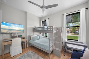 A bedroom with a bunk bed, a desk, a chair, a TV, and a window with curtains. - Refined Coastal 4 Bedroom/4 Bathroom Home with Pool, Spa & Outdoor Kitchen (Naples)