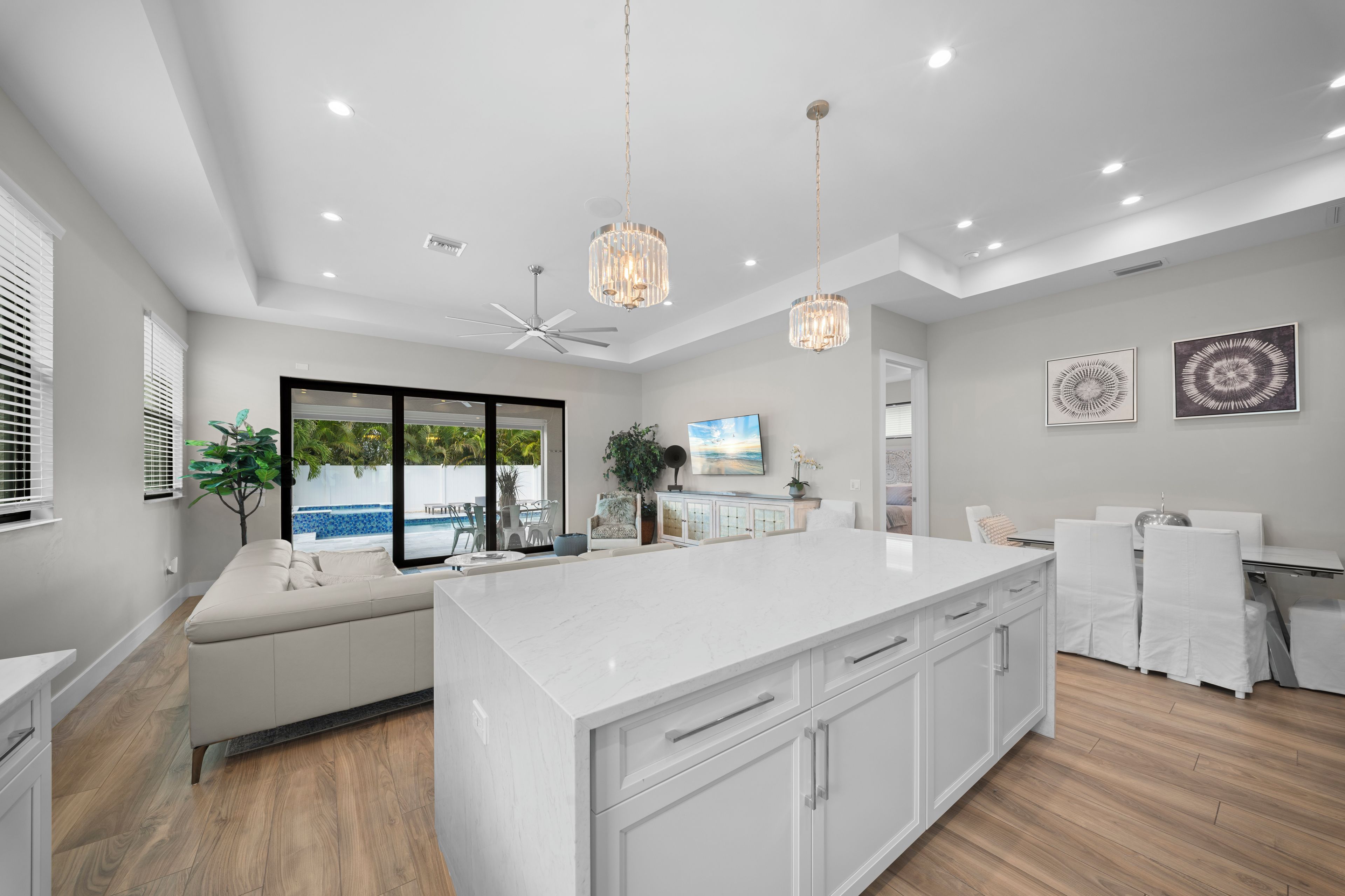 A modern kitchen with a large island, white cabinetry, and a view of a pool.