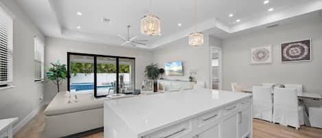 A modern kitchen with a large island, white cabinetry, and a view of a pool.