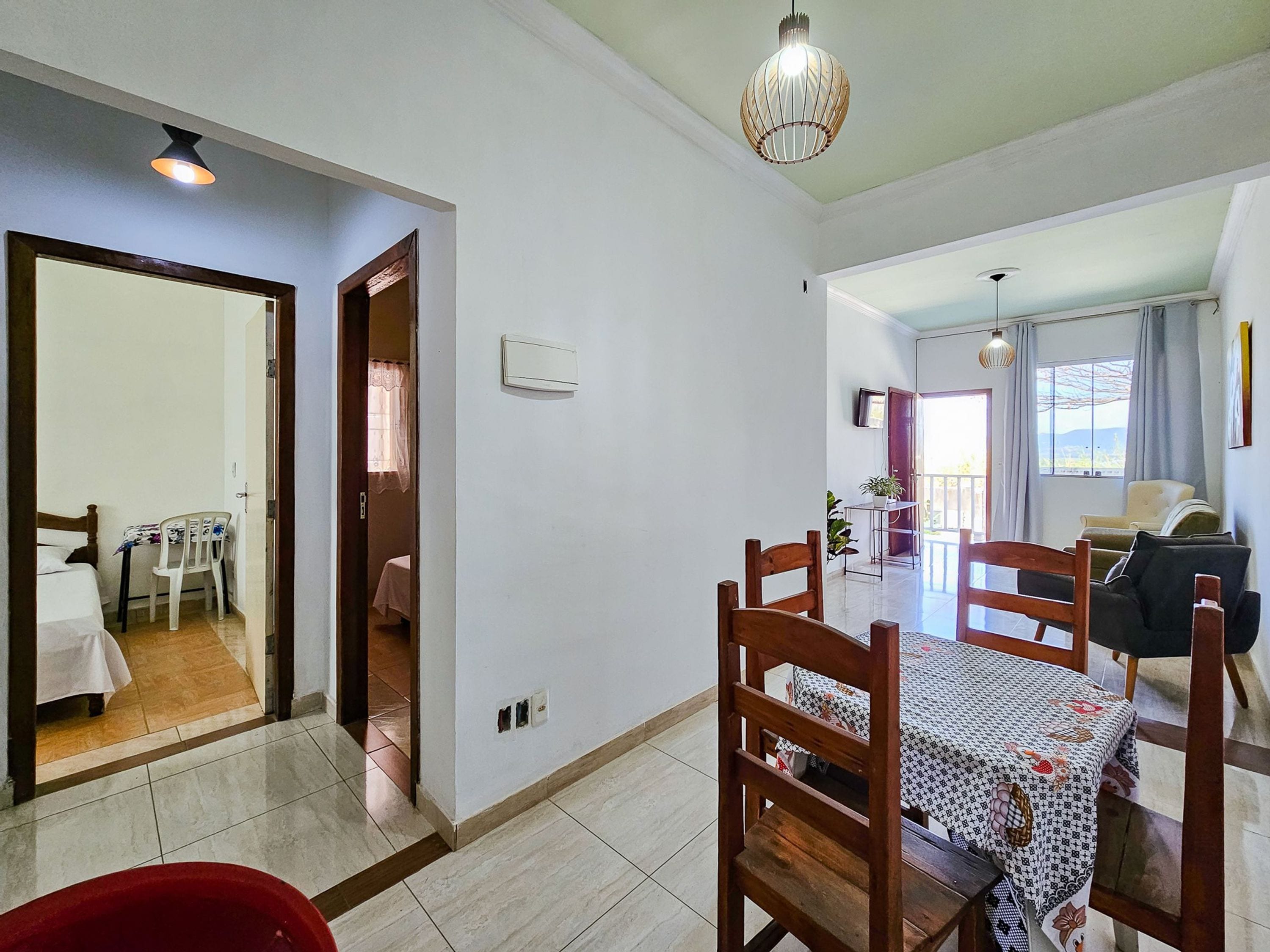 A dining area with a table and chairs, a kitchen visible through an open door, and a living area with a sofa.