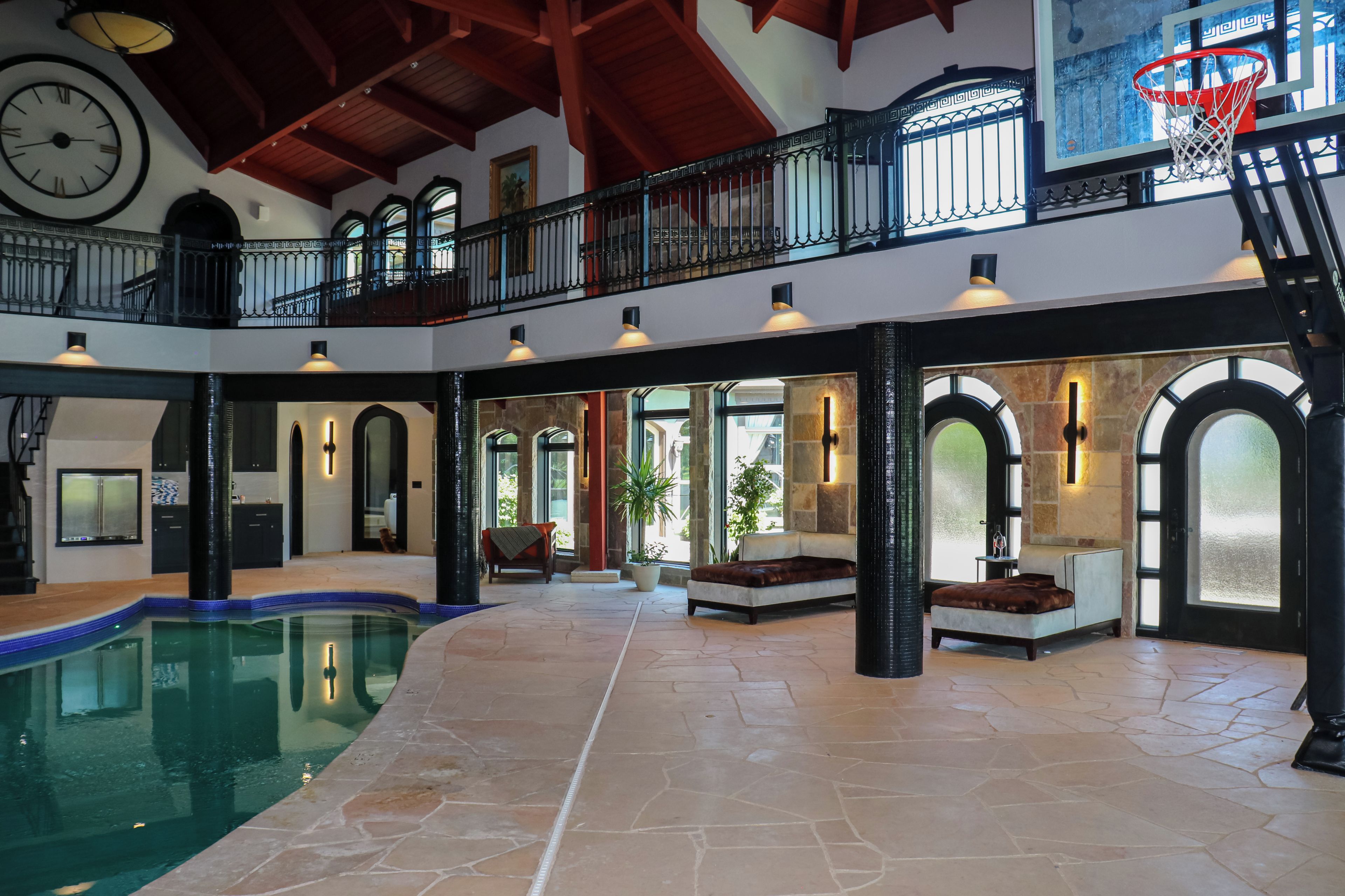 A spacious indoor area with a pool, seating, and a basketball hoop.
