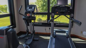 Gimnàs amb equip de cardio, incloent cintes de córrer i una el·líptica, i una panca de peses.