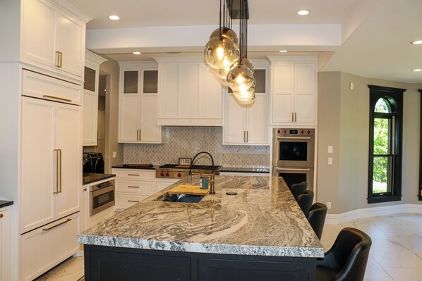 A modern kitchen with white cabinetry, a large island, and a built-in oven.