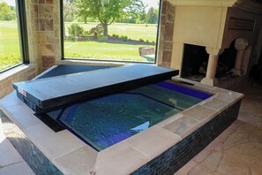 Un jacuzzi con vista a un jardín césped a través de una ventana.