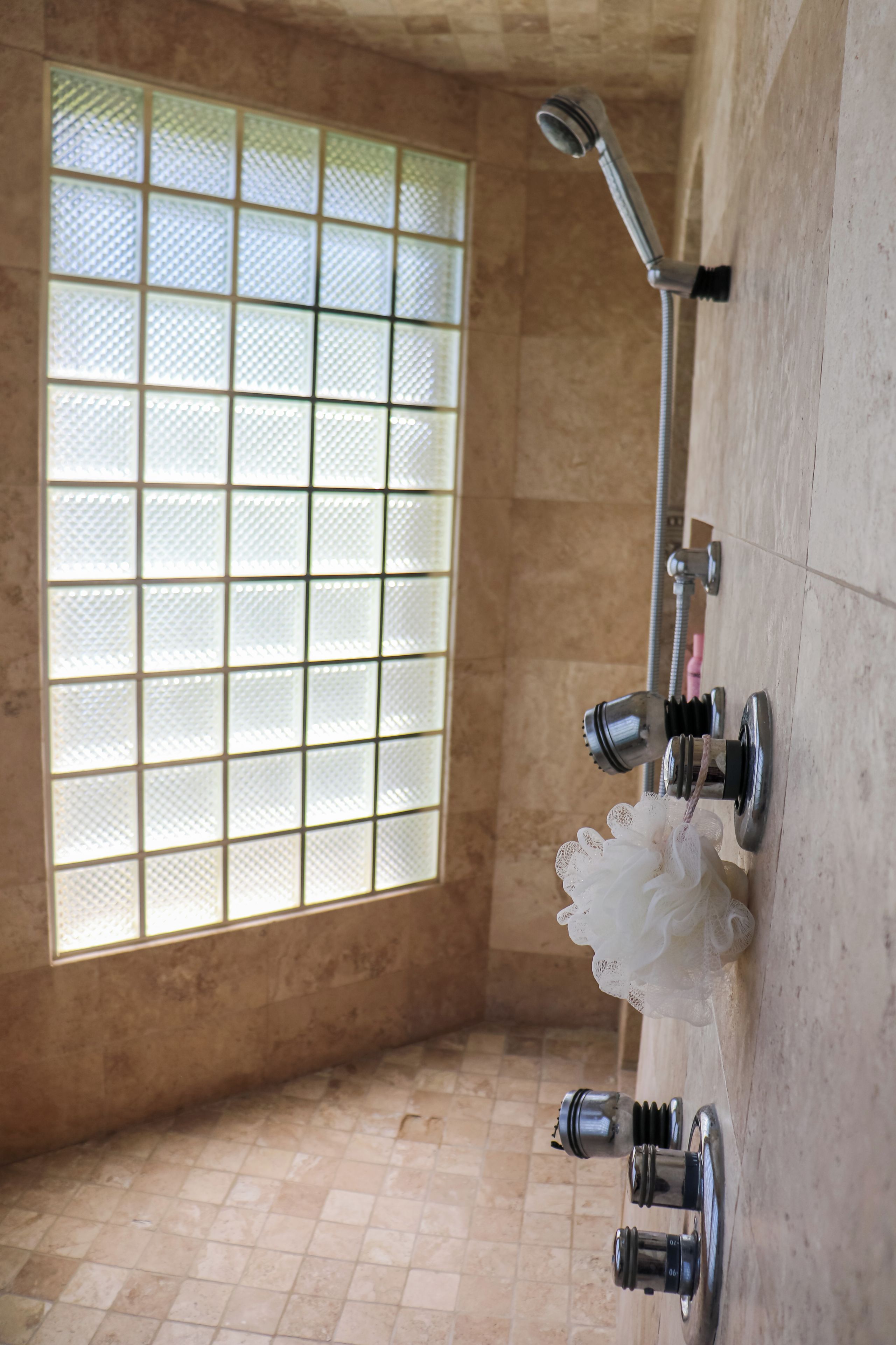 A bathroom with a shower, a window with a grid pattern, and a towel rack with a white towel.