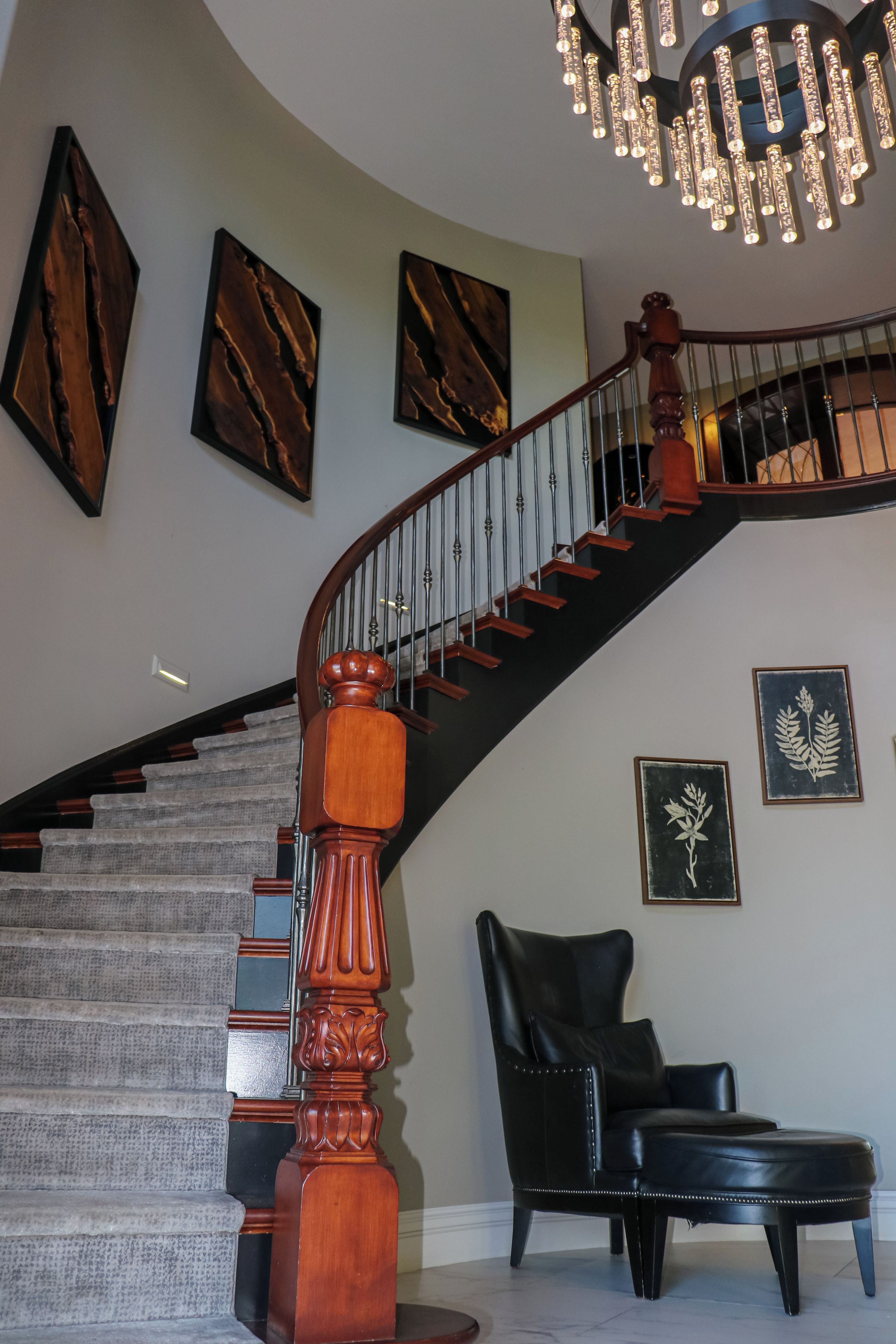 A grand staircase with a wooden handrail and a black leather chair.
