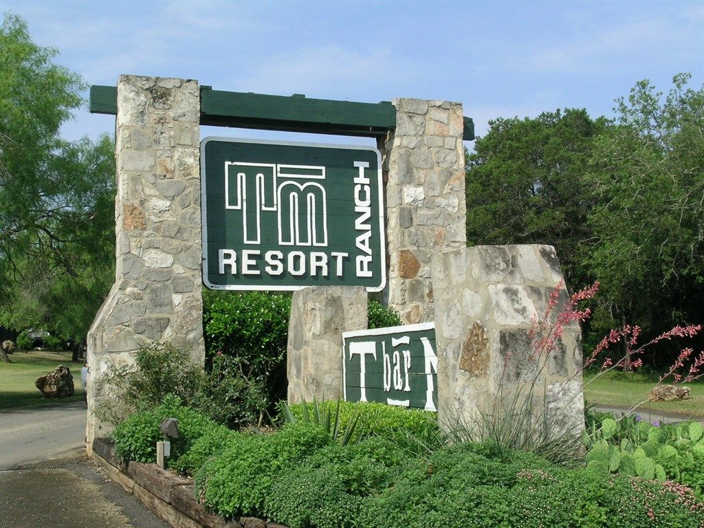 A sign for 'Tm Resort Ranch' with a stone structure and greenery around.