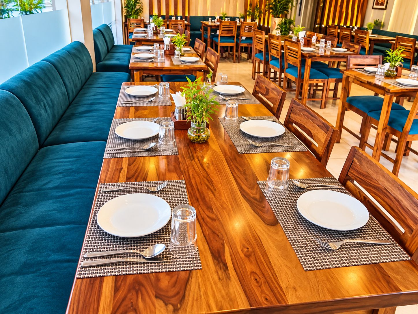 A restaurant with wooden tables, blue cushioned seating, and potted plants.