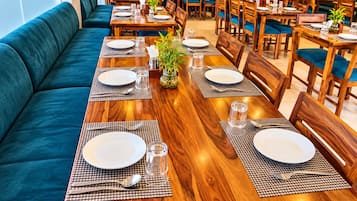 A restaurant with wooden tables, blue cushioned seating, and potted plants.