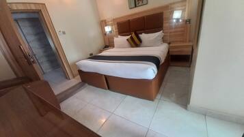Ein Hotelzimmer mit Bett, Nachttisch und einer Tür zu einem Flur.