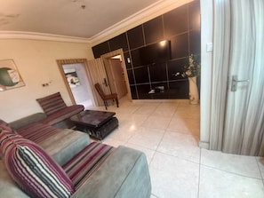 A living room with a sofa, a coffee table, and a TV wall. - Edo Heritage Hotel and Suites Limited (Benin City)
