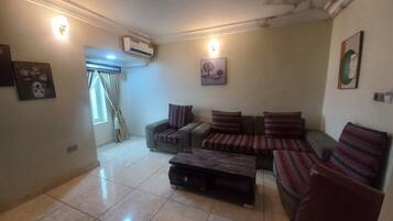 A living room with a sofa set, a coffee table, and a wall-mounted air conditioner.