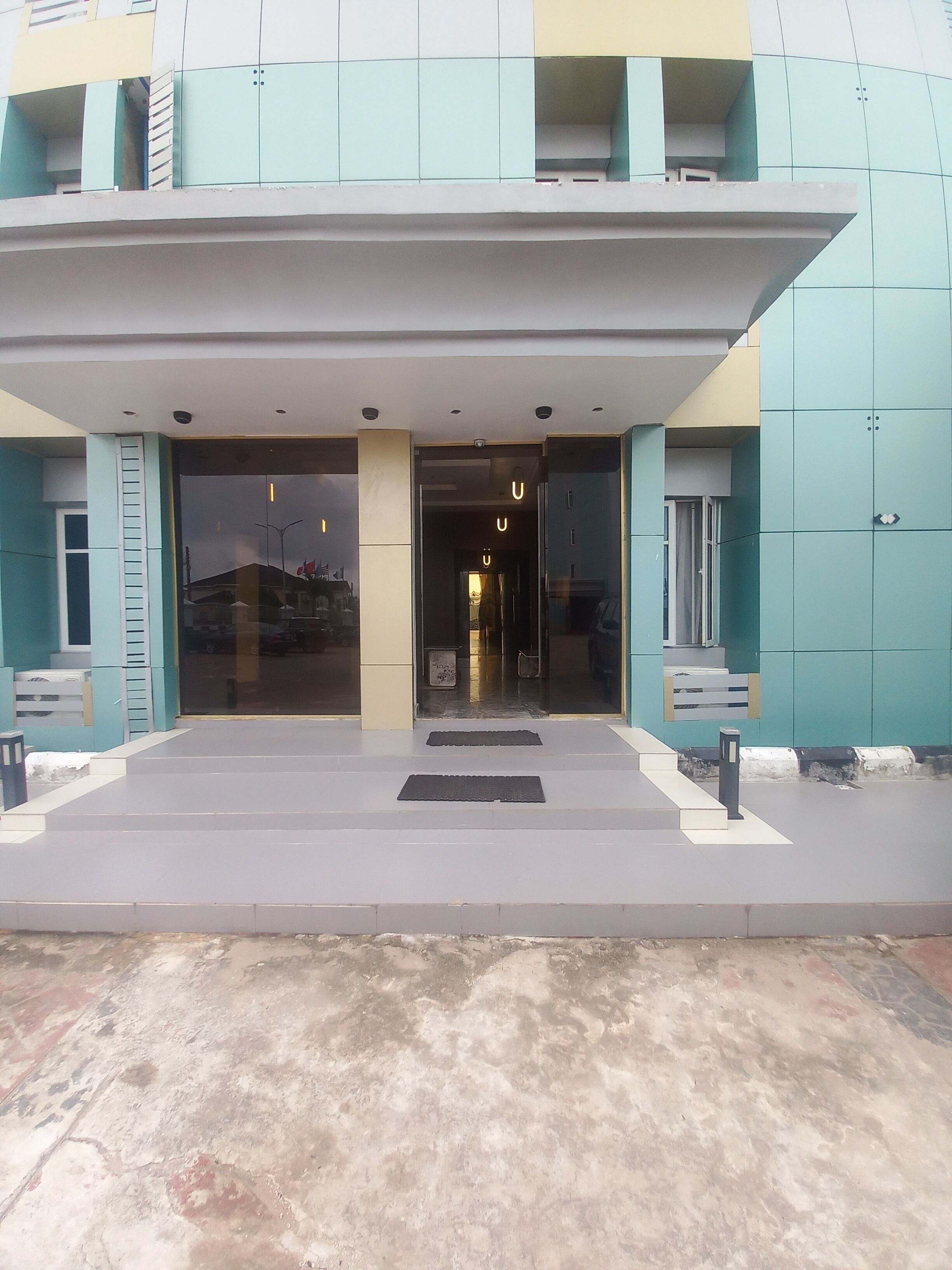 Entrada de un edificio con una marquesina, escalones y una cámara de seguridad.