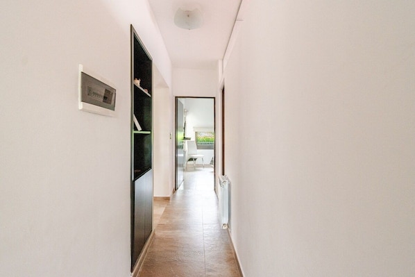 A narrow hallway with a door on the left and a radiator on the right.