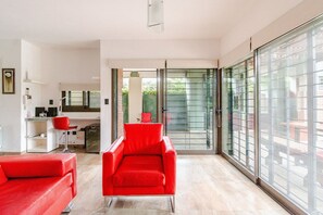 A modern interior with a red chair, a sofa, and a kitchen area.