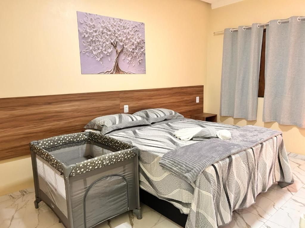Un dormitorio con cama, cabecera, una obra de arte en la pared, una ventana con cortinas y un área pequeña y cerrada con un forro estampado.