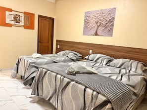 Un dormitorio con dos camas, cabecero de madera, una puerta y un cuadro colgado en la pared.