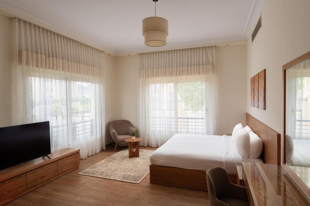 Habitación de hotel con una cama grande, televisión, una silla y una mesita.