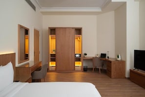 A hotel room with a bed, a desk, a chair, a TV, and a wardrobe. - The 88th Signature by Maran Hospitality (New Cairo)