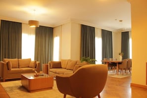 A modern living room with a sofa set, a coffee table, and a dining area with chairs and a table. - The 88th Signature by Maran Hospitality (New Cairo)