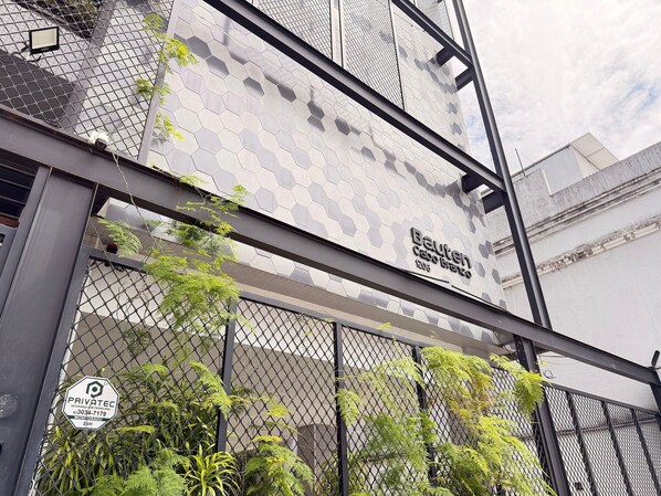 Fachada de edificio con un diseño geométrico, una cámara de seguridad y un letrero que dice 'Bauteh Cabo Branco'.