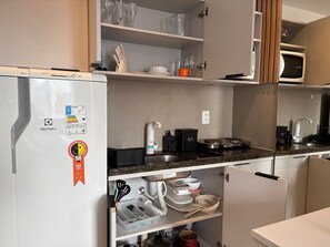 Cocina compacta con refrigerador, microondas y estufa.