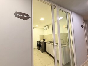 Una cocina moderna con lavadora, un lavamanos y un armario.