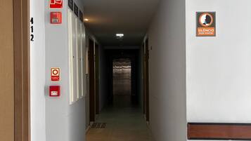 Pasillo de hotel con un detector de incendios, un letrero que dice 'Silencio por favor' y una puerta marcada con el número 412.