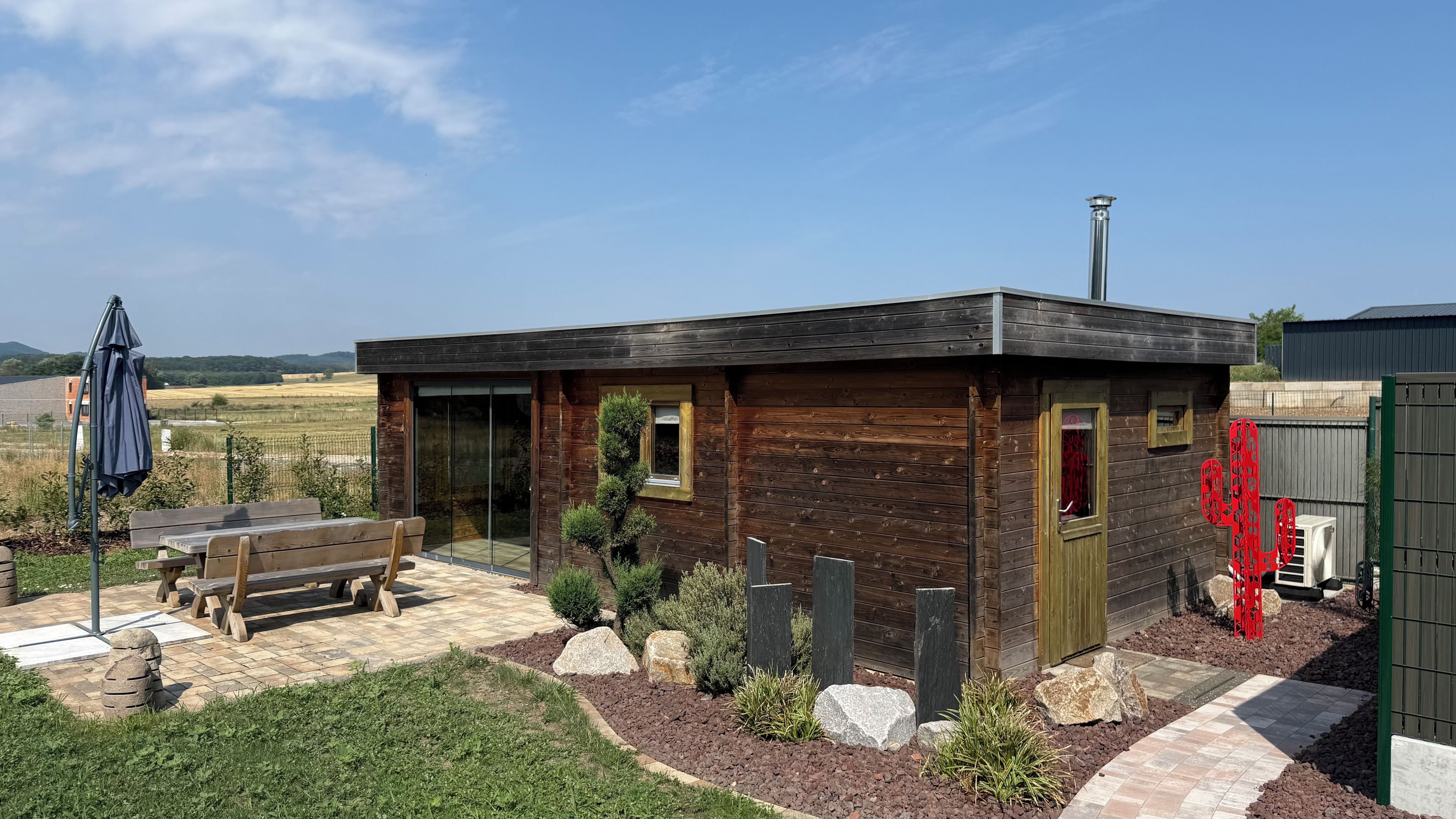 A wooden cabin with a patio, a bench, and a cactus decoration.