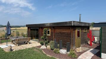 A wooden cabin with a patio, a bench, and a cactus decoration.