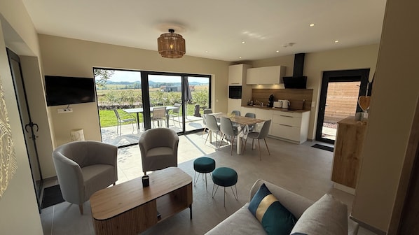 A modern interior with a dining area, kitchen, and a large sliding glass door leading to an outdoor patio.