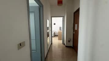 A hallway with a door on the right, a light fixture above, and a window on the left.