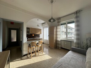 Ein kompakter Wohnbereich mit Küchenzeile, Essplatz und großem Fenster.