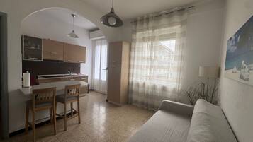 A compact living space with a kitchenette, a dining area, and a sofa.