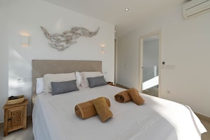 A modern bedroom with a large bed, a decorative wall piece, and a view of the outside. - Villa Cap Blanc, Moraira (Moraira)