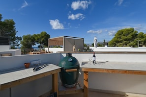 A rooftop terrace with a barbecue grill, a table with a bottle of wine, and a view of the cityscape. - Villa Cap Blanc, Moraira (Moraira)