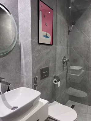 Een moderne badkamer met een wit wastafel, toilet en douche.
