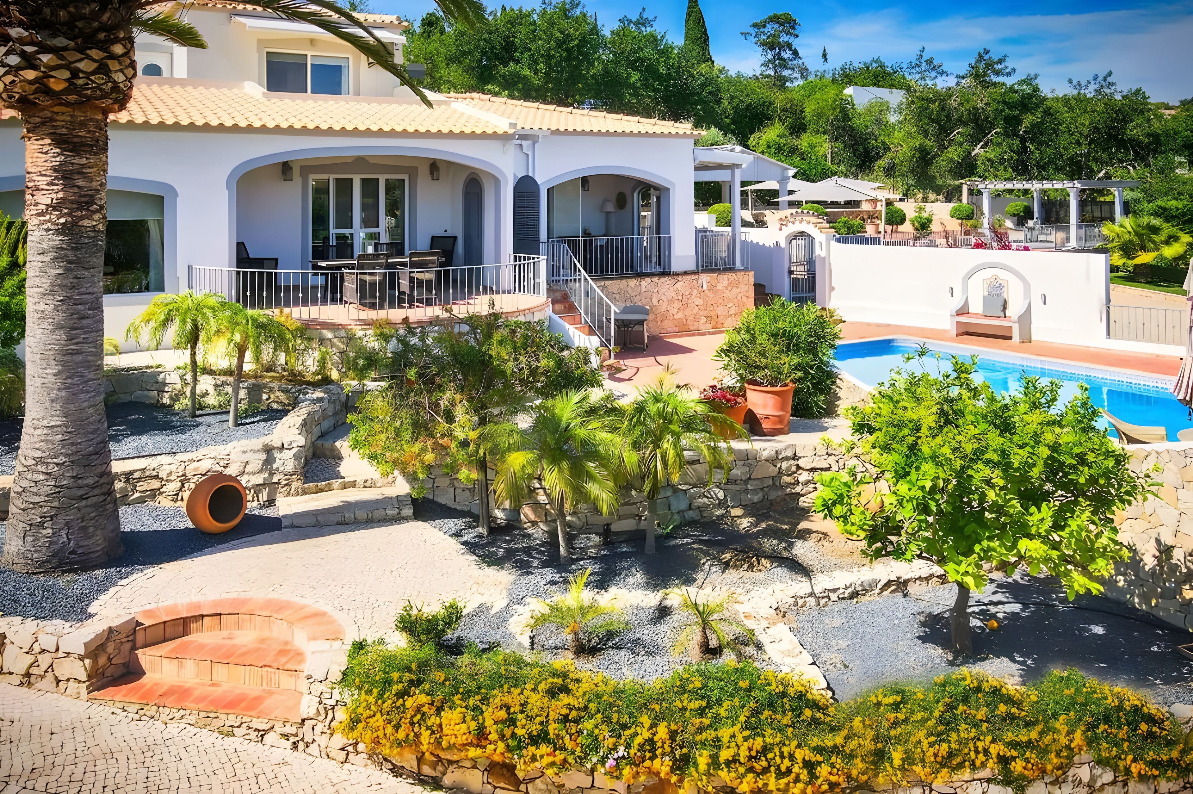 Una villa moderna con piscina, zona de estar exterior y jardín cuidado.