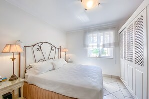Un dormitorio con una cama, dos lámparas de noche, un ventanal y un radiador.
