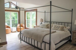 A four-poster bed with a canopy, a chair, a nightstand, and a window with a view of greenery. - Unique 4-bedroom Lake House with Private Dock in Vonore (Vonore)