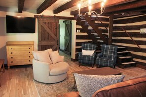 A cozy living room with a wooden ceiling, a wooden chest of drawers, a round armchair, a plaid armchair, and a staircase. - Unique 4-bedroom Lake House with Private Dock in Vonore (Vonore)