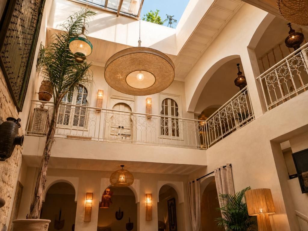 Un intérieur à plusieurs niveaux, agrémenté de portes en arc de cercle, de lampes suspendues et d’un balcon doté d’une balustrade en fer forgé.