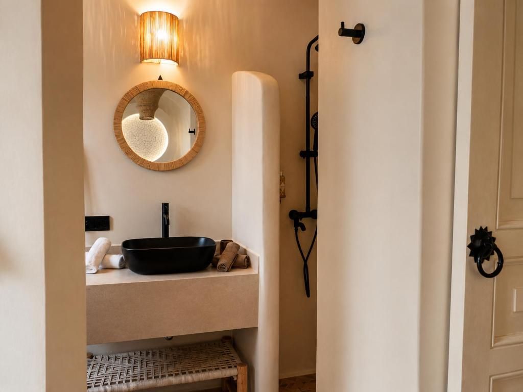 A bathroom with a round mirror, a black basin, and a towel.