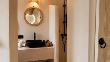 A bathroom with a round mirror, a black basin, and a towel.