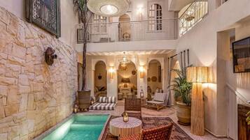 A spacious indoor area with a pool, seating, and a balcony overlooking the pool.