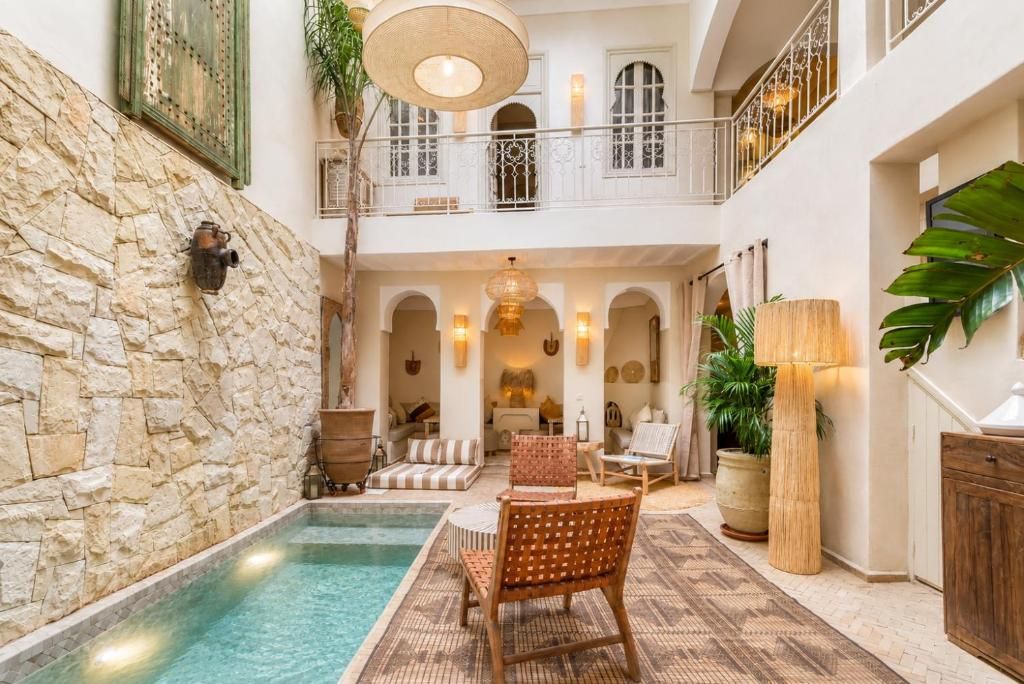 Un área interior amplia con piscina, asientos y una escalera que conduce a un nivel superior.