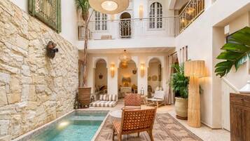Un área interior amplia con piscina, asientos y una escalera que conduce a un nivel superior.