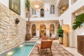 Un área interior amplia con piscina, asientos y una escalera que conduce a un nivel superior.