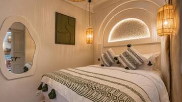 A bedroom with a bed, a mirror, and two wall-mounted lamps.
