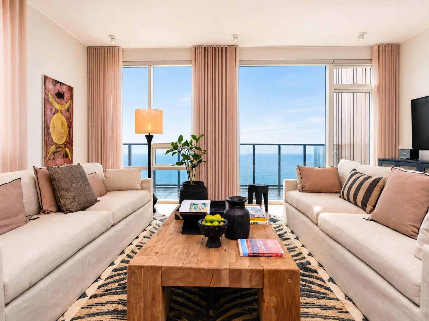 Una sala de estar moderna con dos sofás, una mesa de centro de madera y vista al mar.